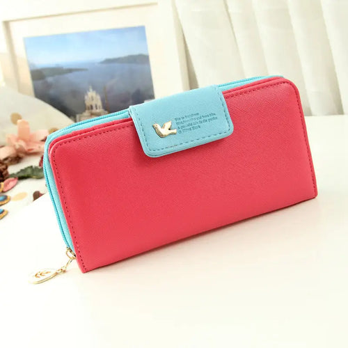 A vibrant pink and light blue designer wallet image with textured faux leather and a gold bird charm flap coin purse
