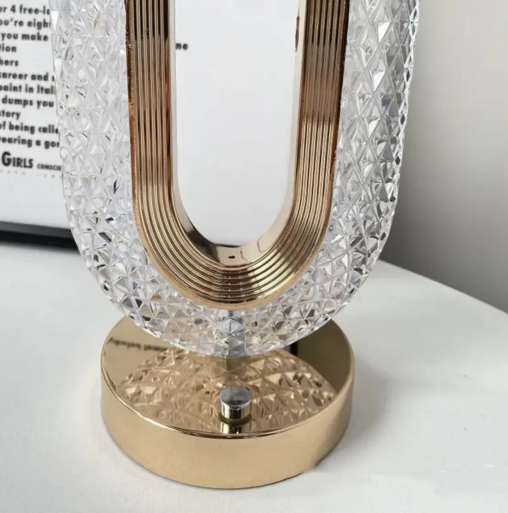 A sleek u-shaped crystal touch desk lamp with gold metallic frame and base for light luxury home decor