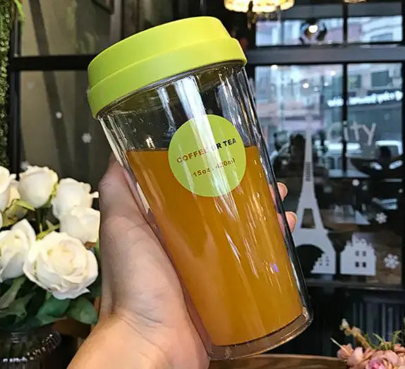 A clear double coffee cup tumbler with a lime green lid filled with amber iced tea from r&z portable double coffee cup