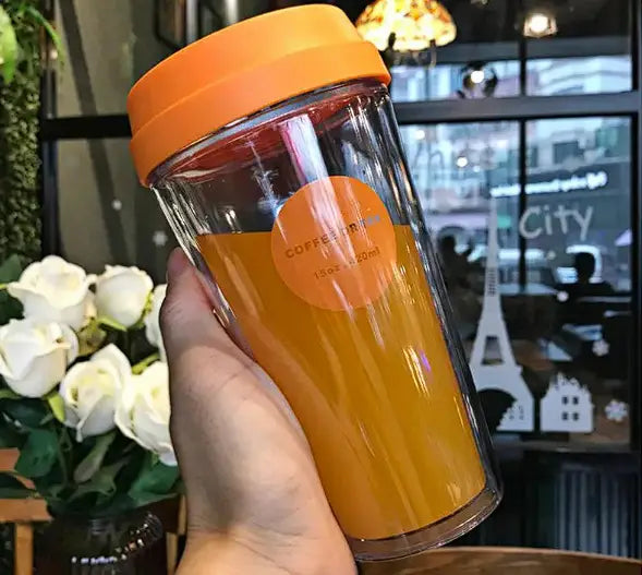 R&z portable double coffee cup with transparent double-walled design orange lid and filled with orange juice