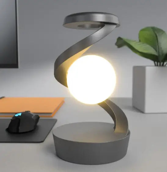 Modern silver rotating moon desk lamp with glowing bulb and wireless charger for stylish office or home use